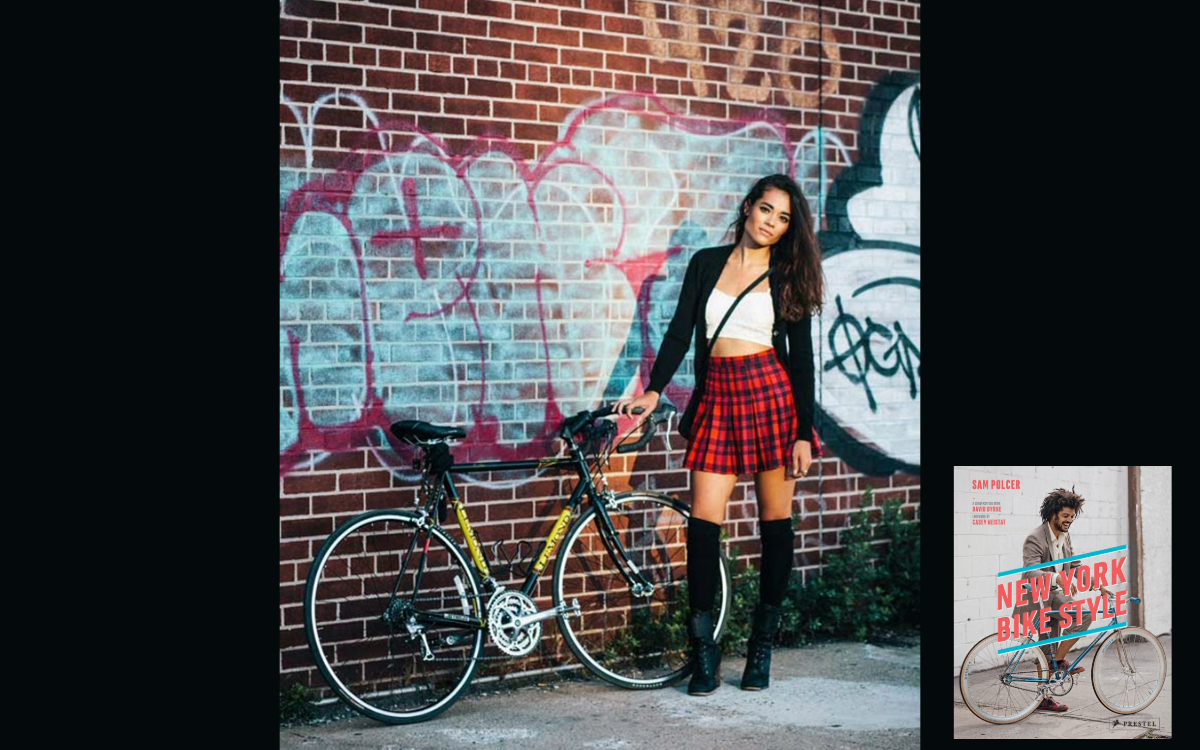 Shannon standing next to road bike in front of brick wall with graffiti